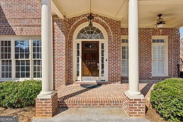 doorway to property with brick siding, covered porch, and a ceiling fan