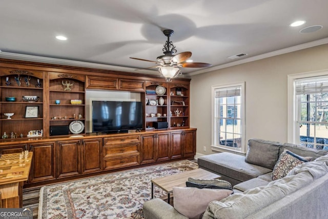 living room with a wealth of natural light, visible vents, and ornamental molding