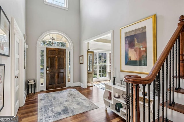 entrance foyer featuring a wealth of natural light, stairway, wood finished floors, and a towering ceiling