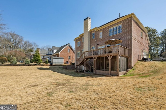 back of property with a yard, fence, brick siding, and a wooden deck