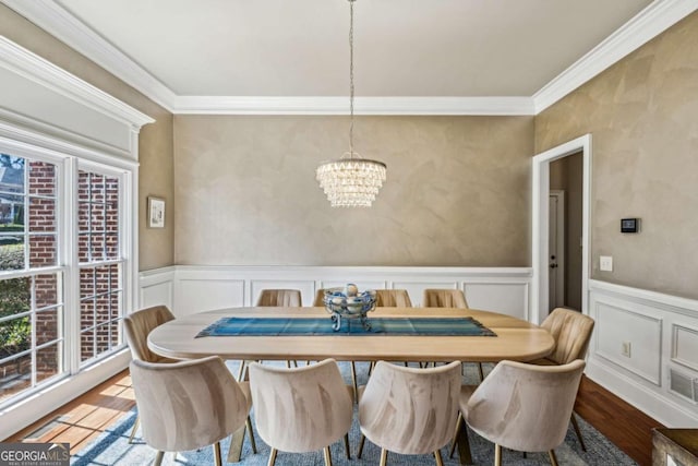 dining space with a chandelier, a wainscoted wall, crown molding, and wood finished floors