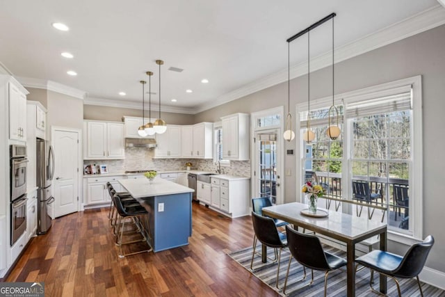 kitchen with a breakfast bar, decorative backsplash, a kitchen island, and light countertops