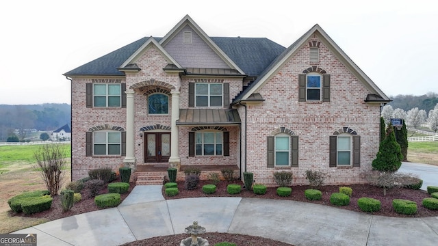 view of front of house with brick siding, french doors, and roof with shingles