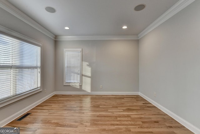 unfurnished room featuring light wood-style floors, baseboards, ornamental molding, and visible vents