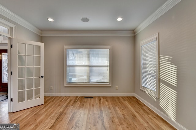 empty room featuring crown molding, baseboards, light wood-type flooring, and visible vents