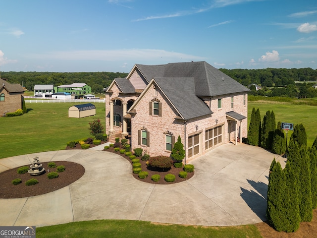 view of front of property with roof with shingles, a garage, brick siding, curved driveway, and a front lawn
