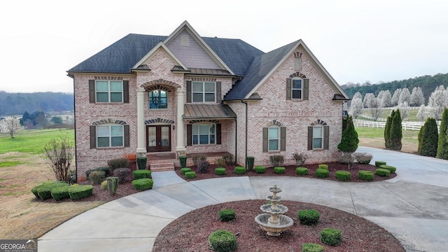 view of front of home with brick siding, curved driveway, fence, french doors, and a standing seam roof