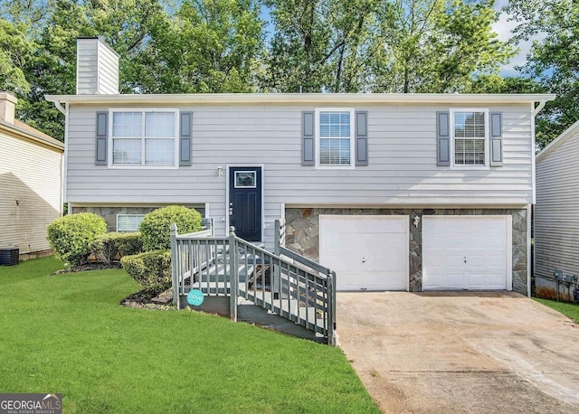 bi-level home with a garage, stone siding, driveway, and a front lawn