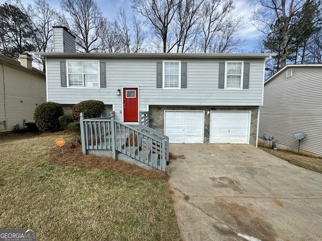 bi-level home with concrete driveway, a chimney, and a garage