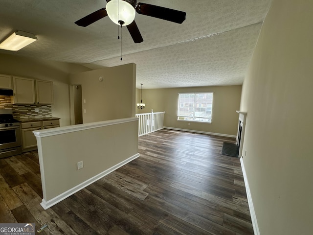 interior space with a ceiling fan, baseboards, dark wood finished floors, a fireplace, and a textured ceiling