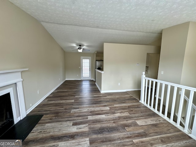 unfurnished living room featuring baseboards, dark wood-type flooring, a fireplace, and a textured ceiling