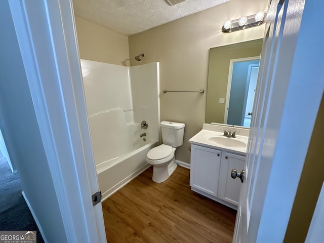 bathroom with vanity, wood finished floors, bathtub / shower combination, a textured ceiling, and toilet