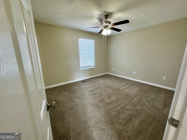 unfurnished bedroom with dark carpet, a textured ceiling, and baseboards