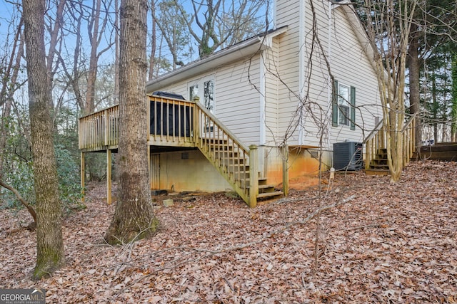 exterior space featuring stairs, a wooden deck, central AC unit, and a chimney