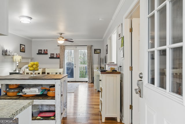 interior space with hardwood / wood-style floors, crown molding, french doors, and a wainscoted wall