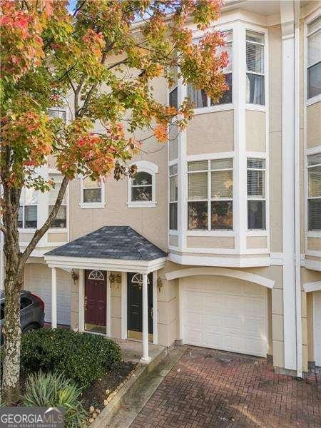 townhome / multi-family property with a garage and stucco siding