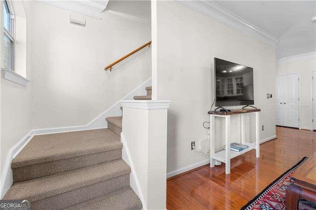 stairway featuring crown molding, wood finished floors, and baseboards