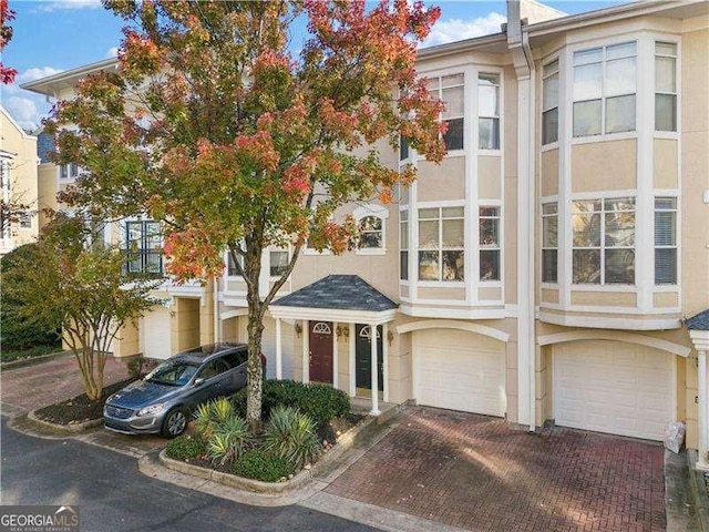 view of property with stucco siding, decorative driveway, and a garage