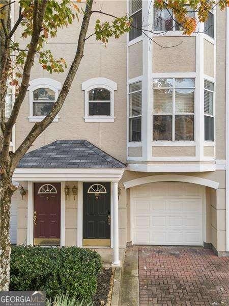 multi unit property featuring decorative driveway, a garage, stucco siding, and roof with shingles