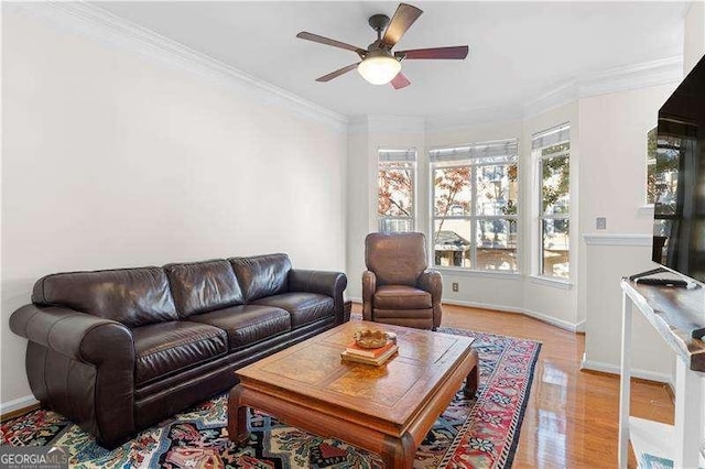 living area with ornamental molding, a ceiling fan, light wood-style flooring, and baseboards