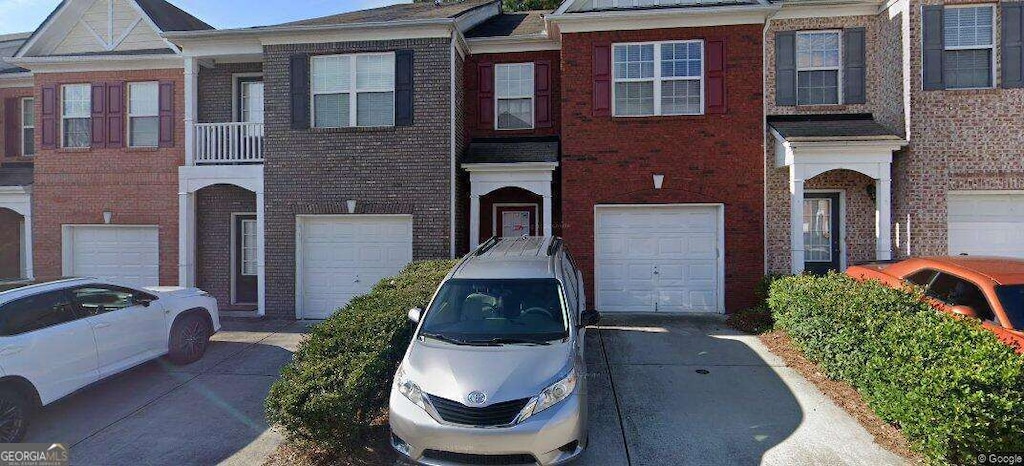 townhome / multi-family property with driveway, brick siding, and an attached garage