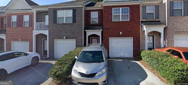 townhome / multi-family property with driveway, brick siding, and an attached garage