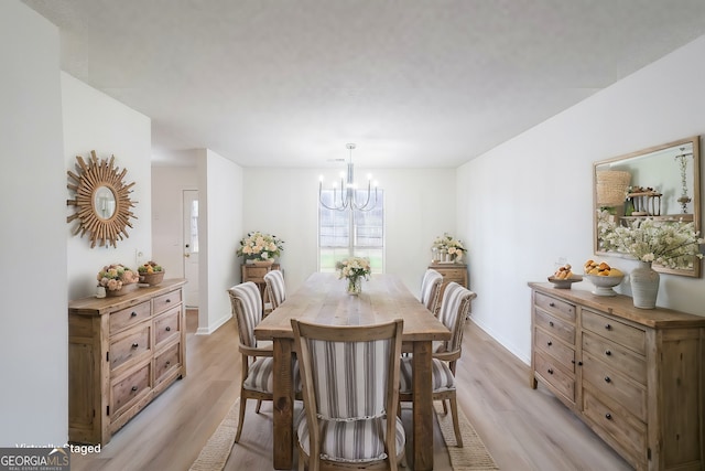 dining space with light wood finished floors, a notable chandelier, and baseboards