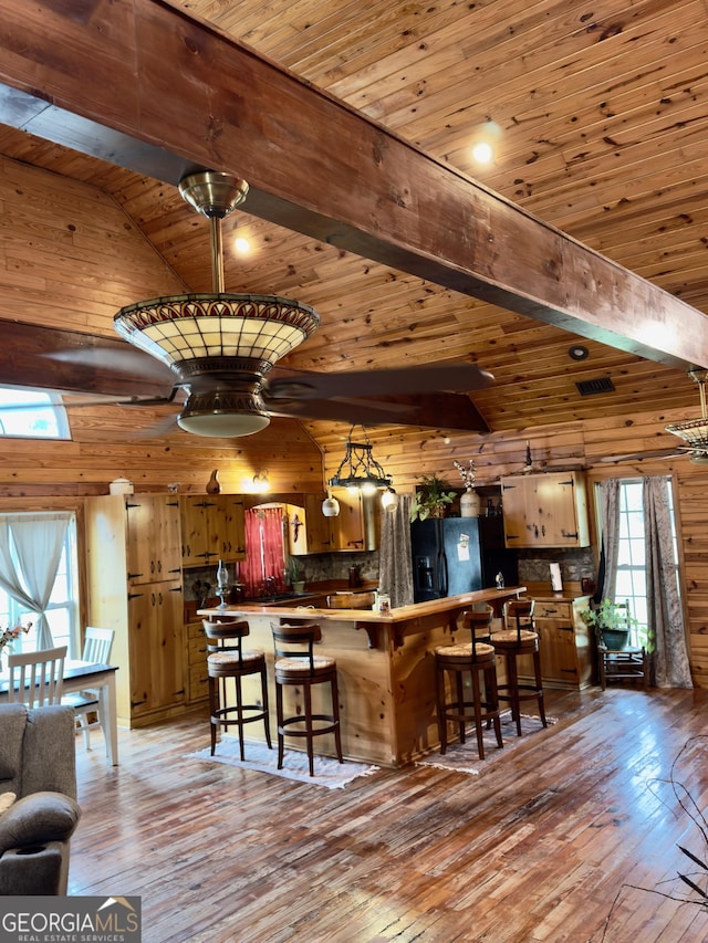 kitchen with beam ceiling, light wood-style floors, wood ceiling, and black refrigerator with ice dispenser