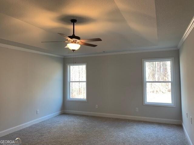 empty room with ceiling fan, crown molding, baseboards, and carpet floors