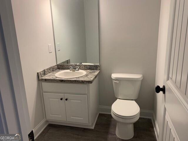 bathroom with vanity, toilet, wood finished floors, and baseboards