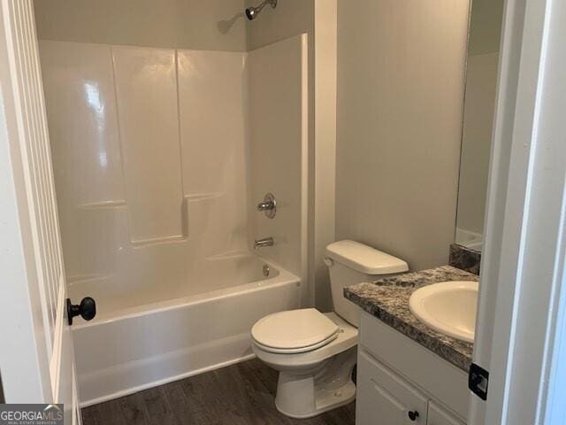 full bathroom featuring washtub / shower combination, toilet, wood finished floors, and vanity