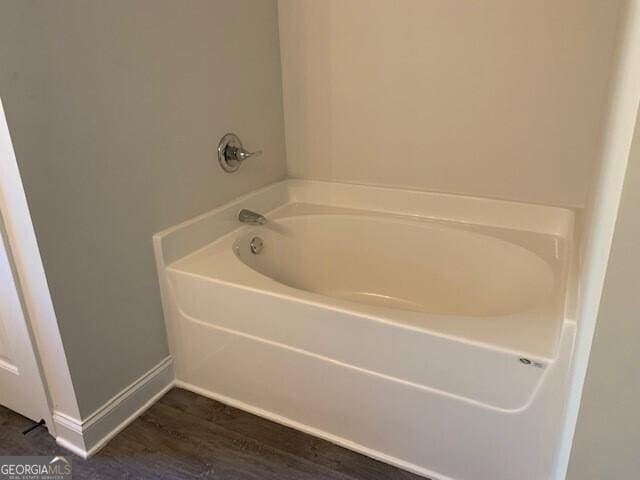 bathroom featuring baseboards, a garden tub, and wood finished floors