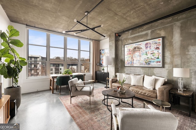 living area featuring finished concrete flooring, baseboards, and a chandelier