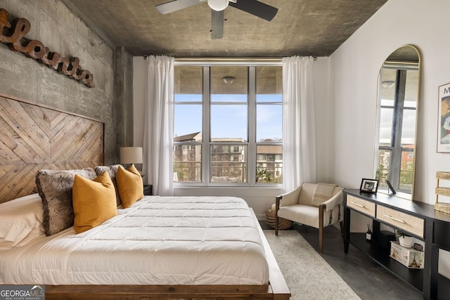 bedroom featuring ceiling fan, multiple windows, and finished concrete flooring