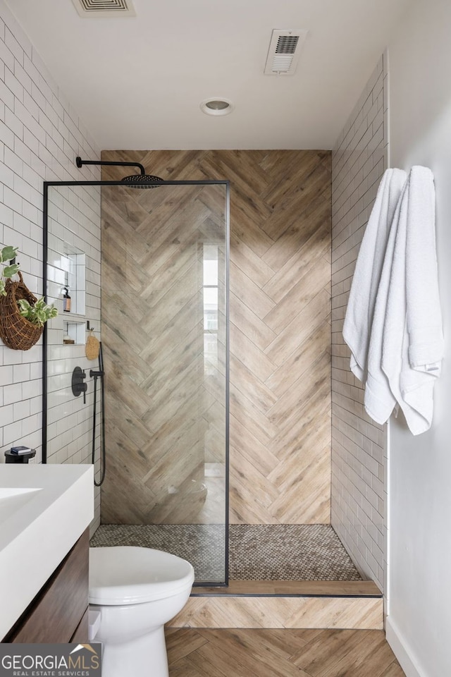 bathroom with vanity, toilet, visible vents, and walk in shower