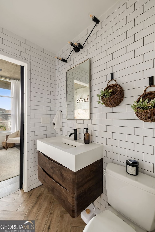 bathroom featuring vanity, tile walls, toilet, and wood finished floors