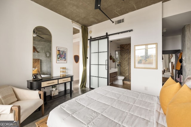 bedroom with a barn door, visible vents, and ensuite bath