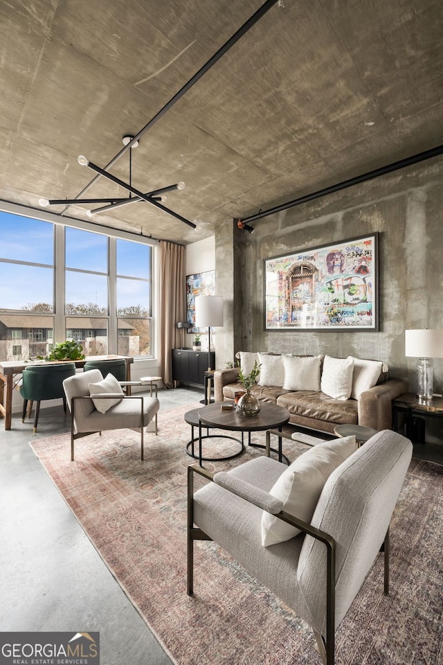 living area featuring concrete flooring and a chandelier