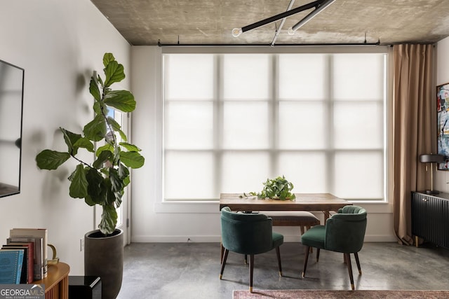 dining room featuring concrete floors, a healthy amount of sunlight, radiator heating unit, and baseboards