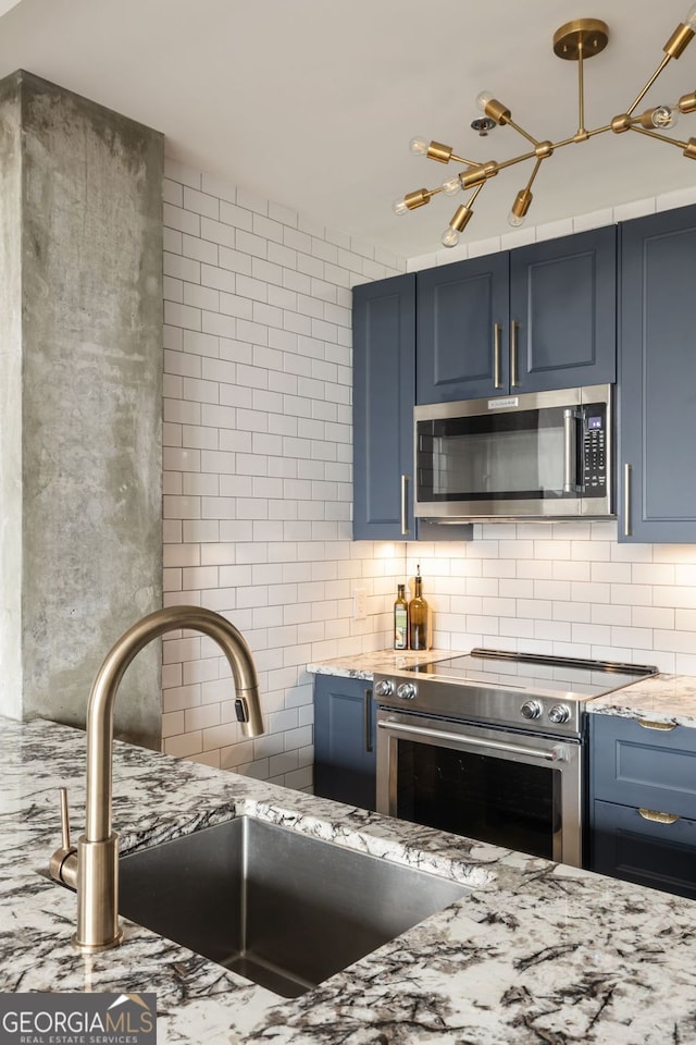 kitchen with a sink, stainless steel appliances, backsplash, and blue cabinets