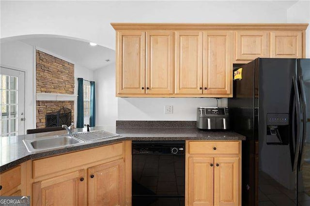 kitchen with a sink, dark countertops, black appliances, and light brown cabinets