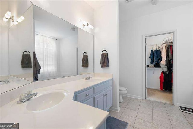 full bath featuring tile patterned floors, toilet, a walk in closet, and a sink