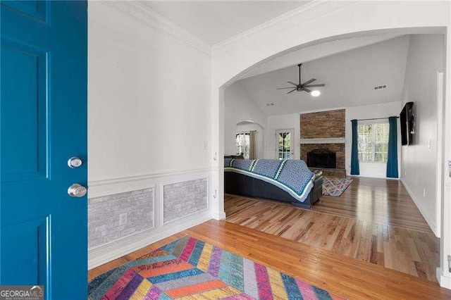 foyer with arched walkways, wood finished floors, a ceiling fan, and ornamental molding