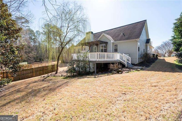 rear view of house with stairway, a yard, fence, and a wooden deck