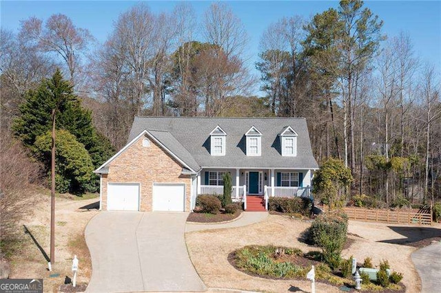 new england style home featuring stone siding, covered porch, driveway, and an attached garage