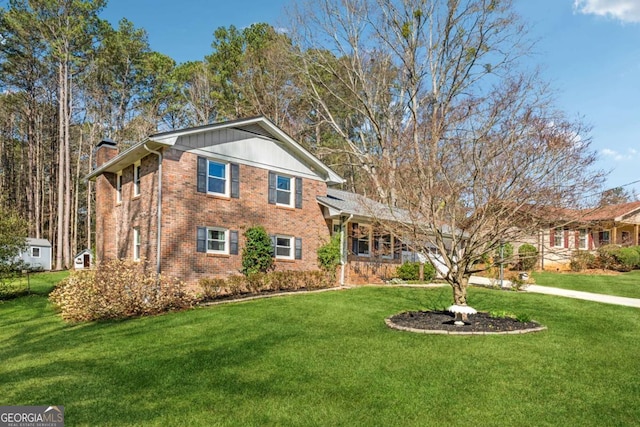 view of front of property with brick siding, a front yard, and a chimney