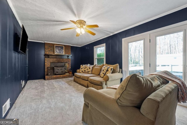 carpeted living room with crown molding, a ceiling fan, visible vents, and a textured ceiling