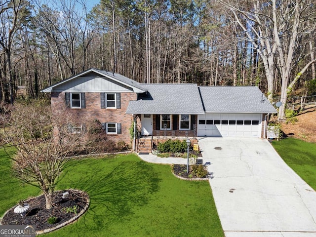 split level home with driveway, a front lawn, an attached garage, a shingled roof, and brick siding