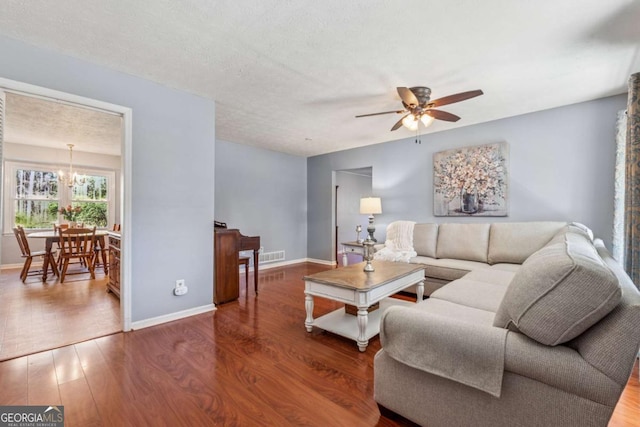 living room featuring ceiling fan with notable chandelier, wood finished floors, and baseboards