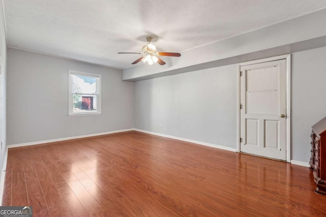 empty room featuring wood finished floors, baseboards, and ceiling fan